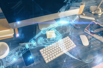 Computer on desktop in office with technology theme hologram. Multi exposure. Tech concept.