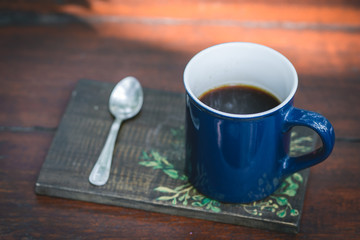 Blue metal coffee cup on wooden table with spoon on the side in chiang mai