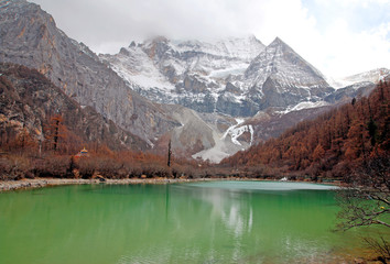 Landscape Pearl Lake with Chenrezig (Xiannairi) Holy Snow Mountain background at Yading winter season. It is beautiful green lake at yading national parks , daocheng china -green nature travel concept