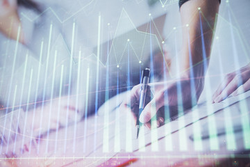 A woman hands writing information about stock market in notepad. Forex chart holograms in front. Concept of research. Double exposure