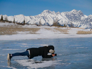 Female photographer takes photos of the slippery frozen surface of Lake Abraham.