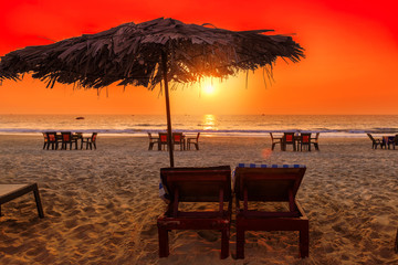 Sunset at tropical beach with lounge chairs and beach umbrellas in GOA, India