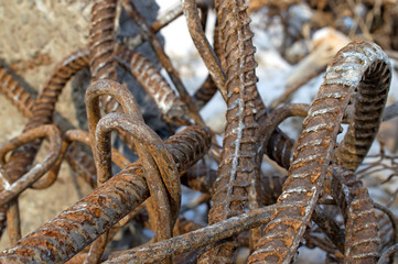 A pile of iron twisted rusty old reinforcing wire lies among the logs on the river bank 2