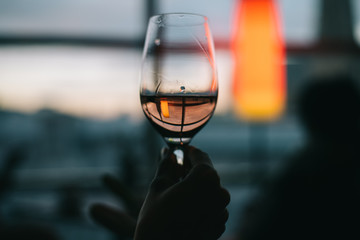 holding a half empty glass of wine at sunset reflects a outside building