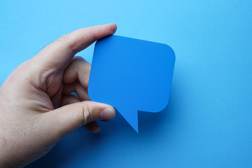 Man holding blank blue speech bubble on blue background.