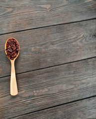 Cacao nibs in a wooden spoon on a old wooden background. Text space.