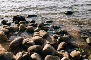 Stones on the lake in the fog. Big and small stones. The water is transparent and under the water you can see stones overgrown with silt. Copy space.