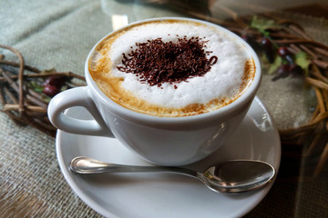 A cup of coffee in a white cup on wooden background.