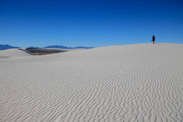 Fototapeta na wymiar Person walking on white sand dunes, White Sands National Monument, New Mexico, USA