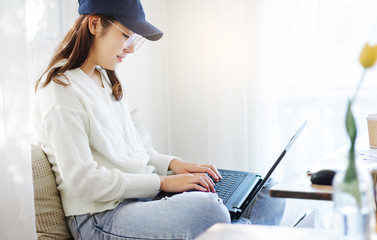 Young female sitting on sofa and placed laptop on the lap to working in living room