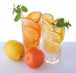 two glasses with lemon and tangerine drink and fruits