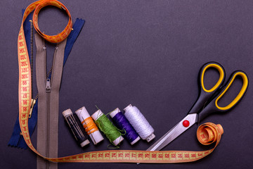 Copyspace frame with sewing tools and accesories. Tools for sewing and handmade: thread, scissors, pins on black paper.