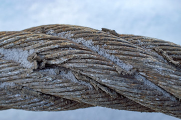 piece of torn worn steel dirty weaved cable under snow