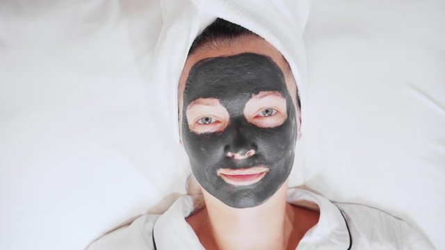 woman with a white towel on her head and black cosmetic mask wellness have fun , spa, skin care