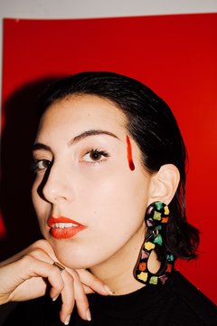 Close up portrait of young woman with earrings and a drop of blood
