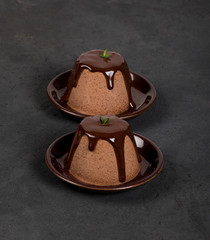 Italian dessert Panna cotta with chocolate sauce on a dark background