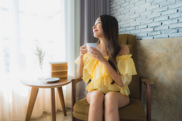 Portrait young asian woman sit on sofa chair and read book with coffee cup