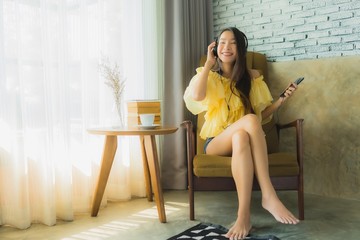 Portrait young asian woman sit on chair listen music with mobile phone coffee and book