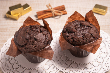 two chocolate muffins on a table with hot chocolate
