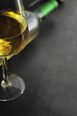 Transparent bottle of white dry wine on the table. White wine glass on a wooden background.