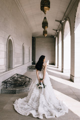 Obraz premium bride in a beautiful white and long dress on a background of building