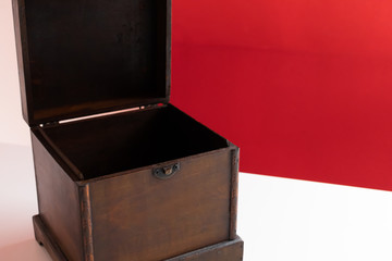Mysterious old wooden box against bright red background on clean white desk