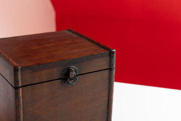 Mysterious old wooden box against bright red background on clean white desk