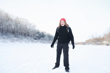 A man travels with a backpack. Winter hike in the forest. Tourist on a walk in the winter in the park.