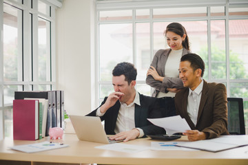 Businessmen are looking at the business plan and business results from the notebook in the office.