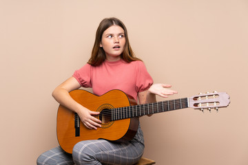 Ukrainian teenager girl with guitar over isolated background with surprise facial expression