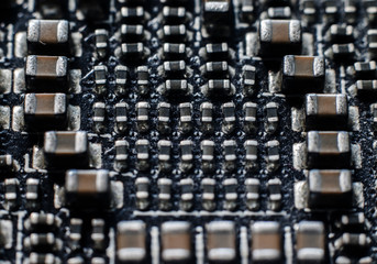 Close up macro on electronic system with integrated circuit chip and capacitors. Old board with dust
