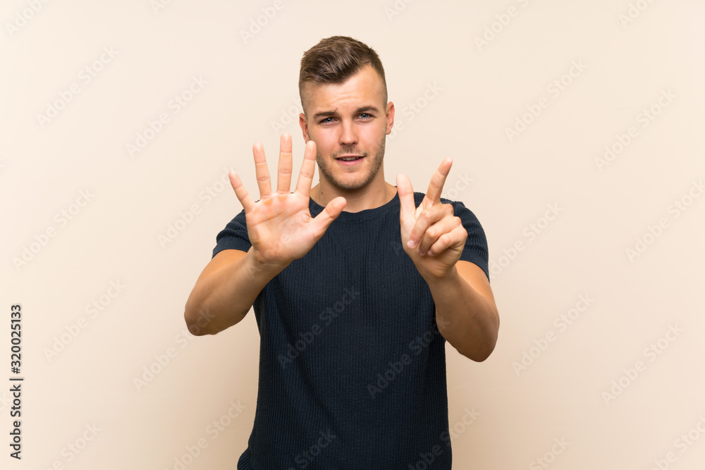 Wall mural Young handsome blonde man over isolated background counting seven with fingers