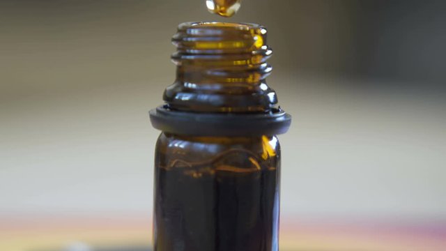 Droplets of Hemp oil going into glass bottle. 