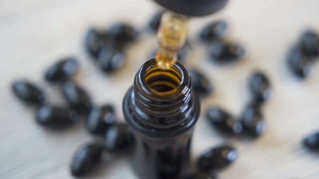 Close loook of Medical worker filling Glass Bottle With Hemp CBD oil using a pipette