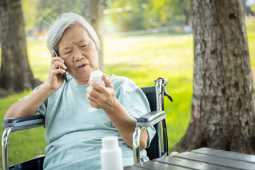 Sick asian senior woman holding bottle of medicine,.calling doctor requesting information,worried female elderly consulting,asking with pharmacist about pill,medical consultation service of hospital