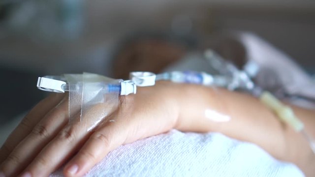 Patients saline, Iv drip, young woman hand with medical drip intravenous needle, give salt water on hospital bed. intravenous therapy (IV) is a therapy that delivers fluids directly into vein.