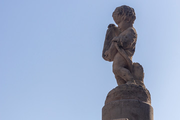 Fototapeta na wymiar White statue of a small child on a background of blue sky.