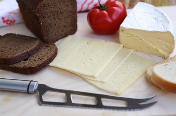 White and black bread, different varieties of cheese and knife view from above