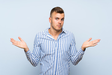 Fototapeta premium Young handsome blonde man over isolated blue background making doubts gesture