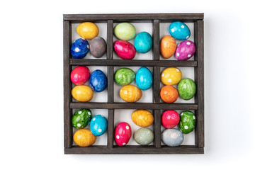 Different easter eggs in wooden box isolated on white