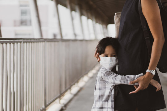 Close up of unhappy asian little girl wearing a mask is hugging her mother on the overpass in the city, concept of affect of air pollution and corona virus outbreak to people life and personal hygiene