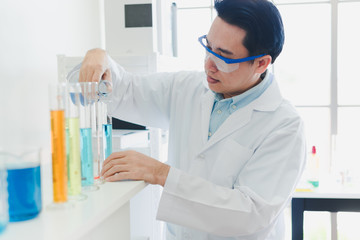 Asian scientists are preparing chemicals for testing and analysis in the laboratory. Scientists clear glasses and white shirts. Science and Chemistry Concept