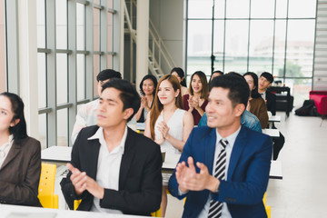 Asian male speaker is speaking at seminars and workshops to the people in the meeting. Attendees applaud the speaker when the meeting is finished