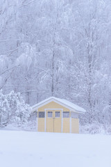 The yellow house in the forest has covered with heavy snow and bad sky in winter season at Tuupovaara, Finland.