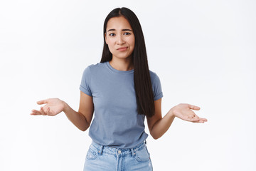Perplexed and indecisive, skeptical cute asian girl cant decide, shrugging with hands spread...