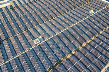 Aerial view of many photo voltaic solar panels mounted of industrial building roof.