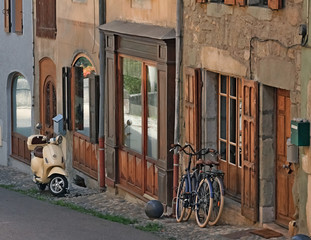 Fototapeta na wymiar Moped and 2 bicycles standing against the wall of an old house. Old city of Alby-sur-Chéran, Savoy, France