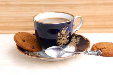 Coffee with milk in a cup, teaspoon of silver and cookies