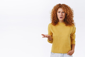 Frustrated, pissed, puzzled serious-looking annoyed redhead curly woman raise one hand in dismay...