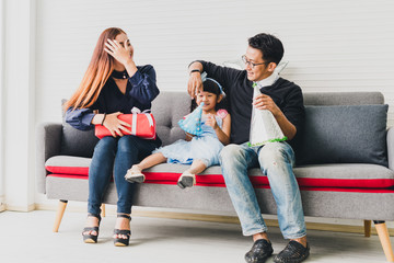 Father, mother and daughter are celebrating Christmas. Christmas hat and a gift for each other. Concept Asian family happiness time.